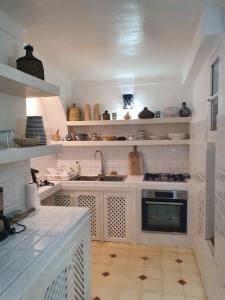 cocina con armarios blancos y fogones en Riad Le Manzil Beldi, en Marrakech