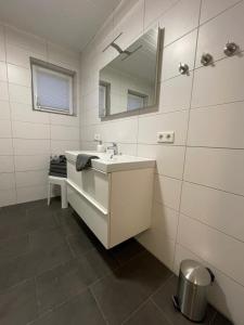 a white bathroom with a sink and a mirror at Ferien Bungalow Ennens in Rhauderfehn +42 photos