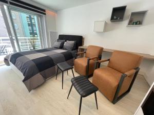 ein Schlafzimmer mit einem Bett und zwei Stühlen in der Unterkunft Groot terras I luxe verblijf I tot 4 personen I 50m van de dijk I Nieuwpoort-Bad in Nieuwpoort