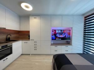 eine Küche mit weißen Schränken und einem Flachbildfernseher in der Unterkunft Groot terras I luxe verblijf I tot 4 personen I 50m van de dijk I Nieuwpoort-Bad in Nieuwpoort