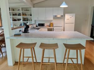 a kitchen with a large counter with three stools at Lark Cottage in Burrawang