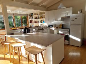a kitchen with white cabinets and a island with bar stools at Lark Cottage in Burrawang