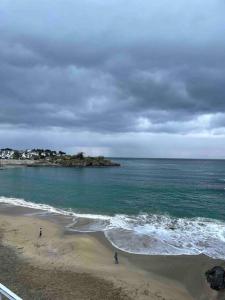 dos personas de pie en una playa cerca del océano en La douce chambrée de Guingamp en Guingamp