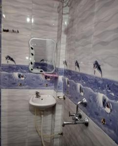 a bathroom with a sink and a shower with dolphins on the wall at Azure Family Paying Guest House in Varanasi