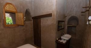 baño con lavabo y aseo y ventana en بيت الصباح نزل وكافيه Bait AlSabah Heritage Inn & Cafe en Birkat al Mawz