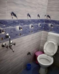 a bathroom with a toilet and penguins on the wall at Azure Family Paying Guest House in Varanasi