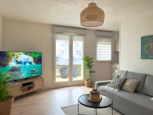 ein Wohnzimmer mit einem Sofa und einem Flachbild-TV in der Unterkunft La Voulzie Appartement - Proche centre avec parking privé in Provins