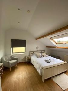 een slaapkamer met een bed, een stoel en een raam bij La Maison de Mel in Bois le Duc