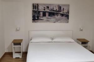 a bedroom with a white bed and two tables at casetta arianna in Brindisi