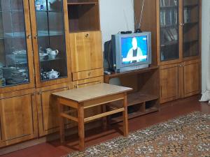 a room with a table and a tv and wooden cabinets at Эконом вариант - спальный район in Chernihiv