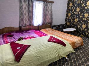 a bedroom with two beds and a window at PK cottage in Pahalgām