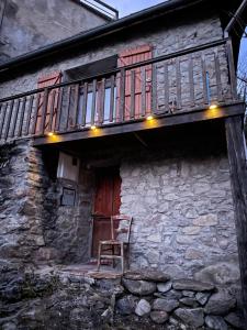 a chair sitting on the porch of a stone building with a balcony at Chalet des Pyrénées in Capoulet-et-Junac