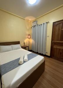 ein Schlafzimmer mit einem Bett mit zwei weißen Handtüchern darauf in der Unterkunft Elisha's Guest House in Coron