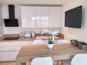 kuchnia z drewnianym stołem i białymi krzesłami w obiekcie Résidence Graziella Appartement 621 w mieście Juan-les-Pins