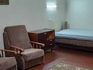 ein Schlafzimmer mit einem Bett, einem Stuhl und einer Kommode in der Unterkunft Эконом вариант - спальный район in Tschernihiw