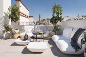 um pátio com cadeiras brancas e uma mesa na varanda em Mylu Suites by Puerta Catedral em Sevilha