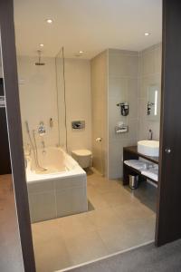a bathroom with a tub and a toilet and a sink at Hotel du Pasino in Saint-Amand-les-Eaux