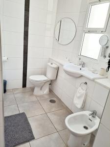La salle de bains blanche est pourvue de toilettes et d'un lavabo. dans l'établissement Light and cosy apartment in 100 meters from the beach Costa Adeje, à Adeje