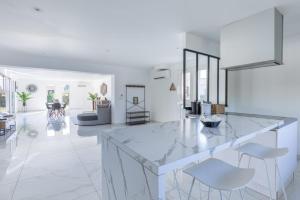 - une cuisine blanche avec un grand comptoir en marbre et des chaises dans l'établissement Villa saint helene, à Sainte-Hélène