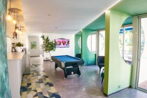a room with a pool table in a room with green walls at Hotel Le Quetzal in La Grande-Motte