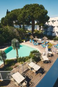 balcón con sillas y piscina en Hotel Le Quetzal, en La Grande-Motte