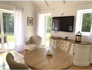 een woonkamer met een tafel en een flatscreen-tv bij Beautiful little house renovated in nature 