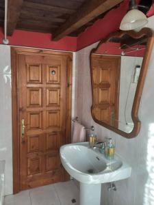 uma casa de banho com um lavatório, um espelho e uma porta em Casa rústica en Dobres con vistas a la montaña em Dobres