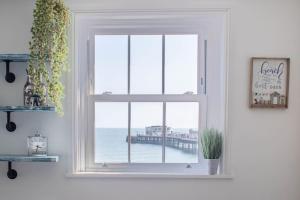 ein Fenster in einem Zimmer mit Blick auf einen Pier in der Unterkunft Lovely 2- Bedroom Apartment with Stunning Sea Views in Worthing