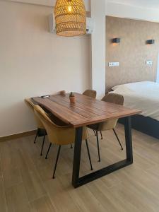 a wooden table and chairs in a room with a bed at Studio Don Jim Family, Beautiful luxurious new Studio near Arenal beach in Jávea