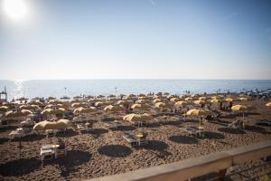 a large group of chairs and umbrellas on a beach at Rubino a soli 150m dal mare con posto auto in Marina di Castagneto Carducci