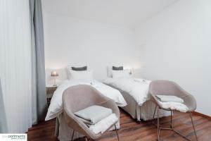 1 dormitorio con 2 camas y 2 sillas en Aasee Apartment in top Lage 80m² mit 2 Schlafzimmern en Münster