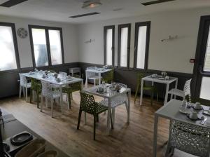 a dining room with tables and chairs and windows at A l'Orée de la Forêt in Campénéac