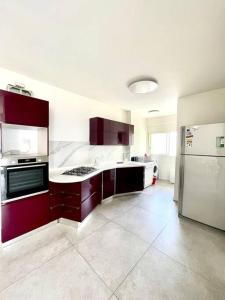 een keuken met rode kasten en een groot apparaat bij SVW Apartment on the Beach in Netanya