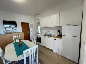 a kitchen with a table and a sink and a refrigerator at Apartman Emilija in Vinišće