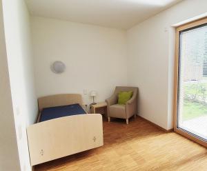 een slaapkamer met een bed, een stoel en een raam bij Barrierefreies Apartment Ursulinenhof in Oberried