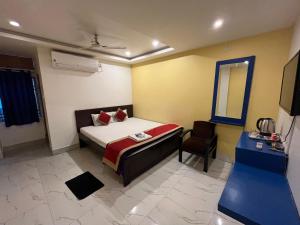 um quarto com uma cama, uma cadeira e um espelho em Hotel Shivanand em Siliguri