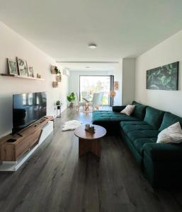 ein Wohnzimmer mit einem grünen Sofa und einem TV in der Unterkunft Chill Panorama Apartman in Siófok