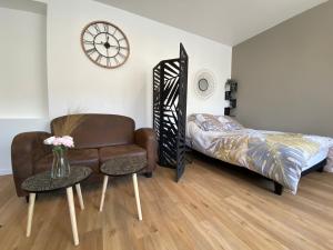 ein Wohnzimmer mit einem Stuhl, einem Bett und einer Uhr in der Unterkunft Brown Cosy in Louviers