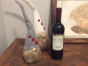 a bottle of wine next to two gnome statues at lo Tsanty in Aosta +3 photos