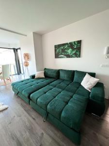 ein großes grünes Sofa im Wohnzimmer in der Unterkunft Chill Panorama Apartman in Siófok