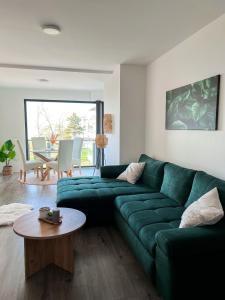 ein Wohnzimmer mit einem grünen Sofa und einem Tisch in der Unterkunft Chill Panorama Apartman in Siófok