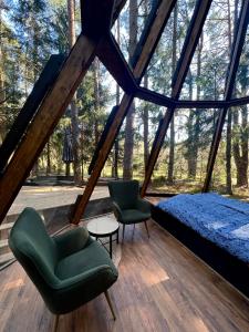 a room with a bed and two chairs and a table at CallTipi glass house in Kalgriaužiai