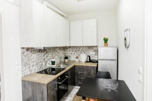 a kitchen with white cabinets and a table and a refrigerator at KNL luxury apartment by homebrain in Alexandroupoli