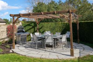 a patio with a table and chairs and a grill at Luxurious 5-Bed House with Pool, Hot Tub & Parking in Eastry