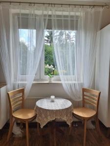 a table and two chairs in front of a window at Domek na wsi. in Kazimierz Dolny