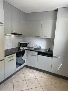 una cucina bianca con lavandino e forno a microonde di Appartamento 464 nel CUORE di Locarno con piscina a Locarno