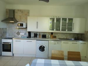 a kitchen with white cabinets and a washing machine at Superbe Villa Piscine Le Céladore de Sarlat Climatisé, 7 Min à pied du Centre in Sarlat-la-Canéda