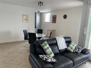 un soggiorno con divano in pelle nera e cuscini di Appartamento 464 nel CUORE di Locarno con piscina a Locarno