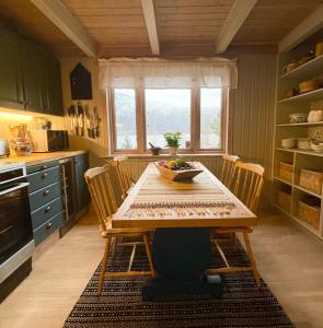 a kitchen with a wooden table with chairs and a window at Secluded Holiday Home, With private beach in Ålesund