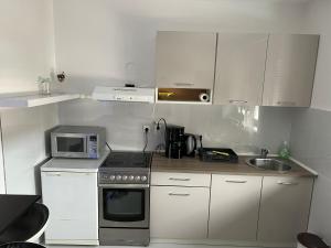 a small kitchen with a stove and a microwave at Apartman Paola - massage chair- 0-24 self check IN OUT- Županja in Županja +10 photos